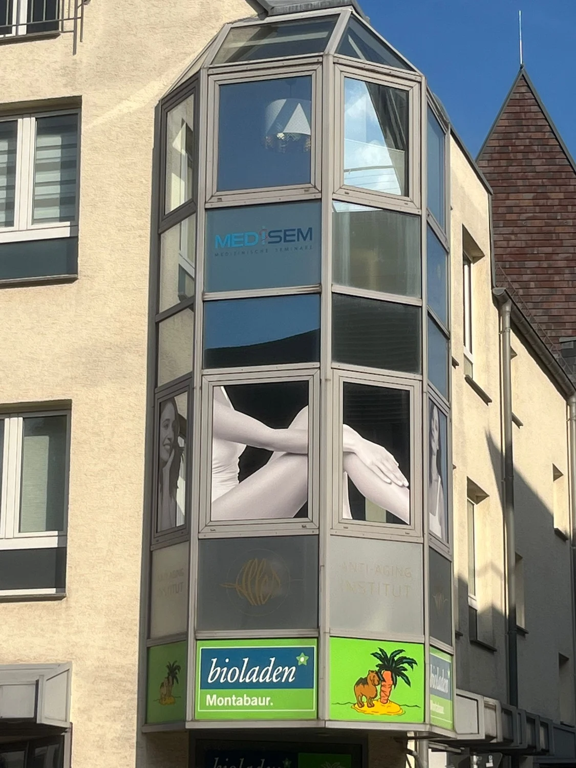 Medisem - Medizinische Seminare - Ein verglaster Gebäudeteil mit einem blauen Logo, auf dem „MEDISEM“ steht, auf einer der Glasscheiben.